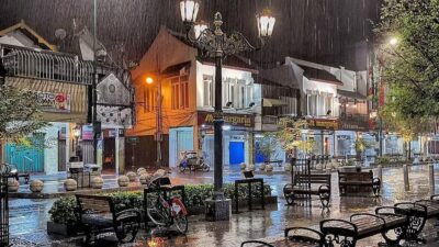 alan Malioboro Yogyakarta saat malam hari diguyur hujan, terlihat bangku-bangku kosong, lampu jalan menyala, serta pantulan cahaya di aspal basah yang menciptakan suasana tenang dan syahdu.